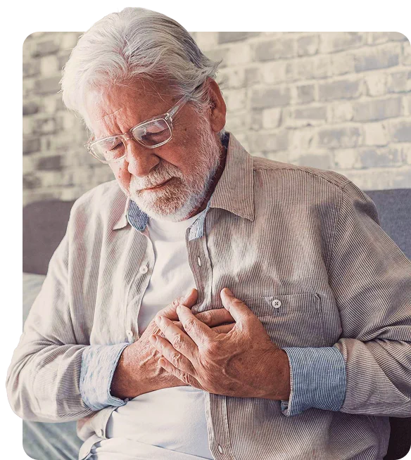 Senior man with glasses holding his chest, appearing concerned indoors.