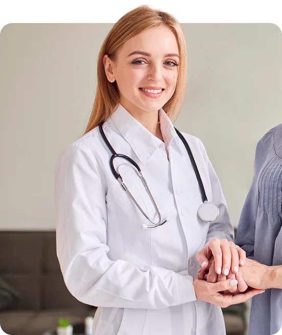Female doctor in a white coat smiling while holding hands with a patient.